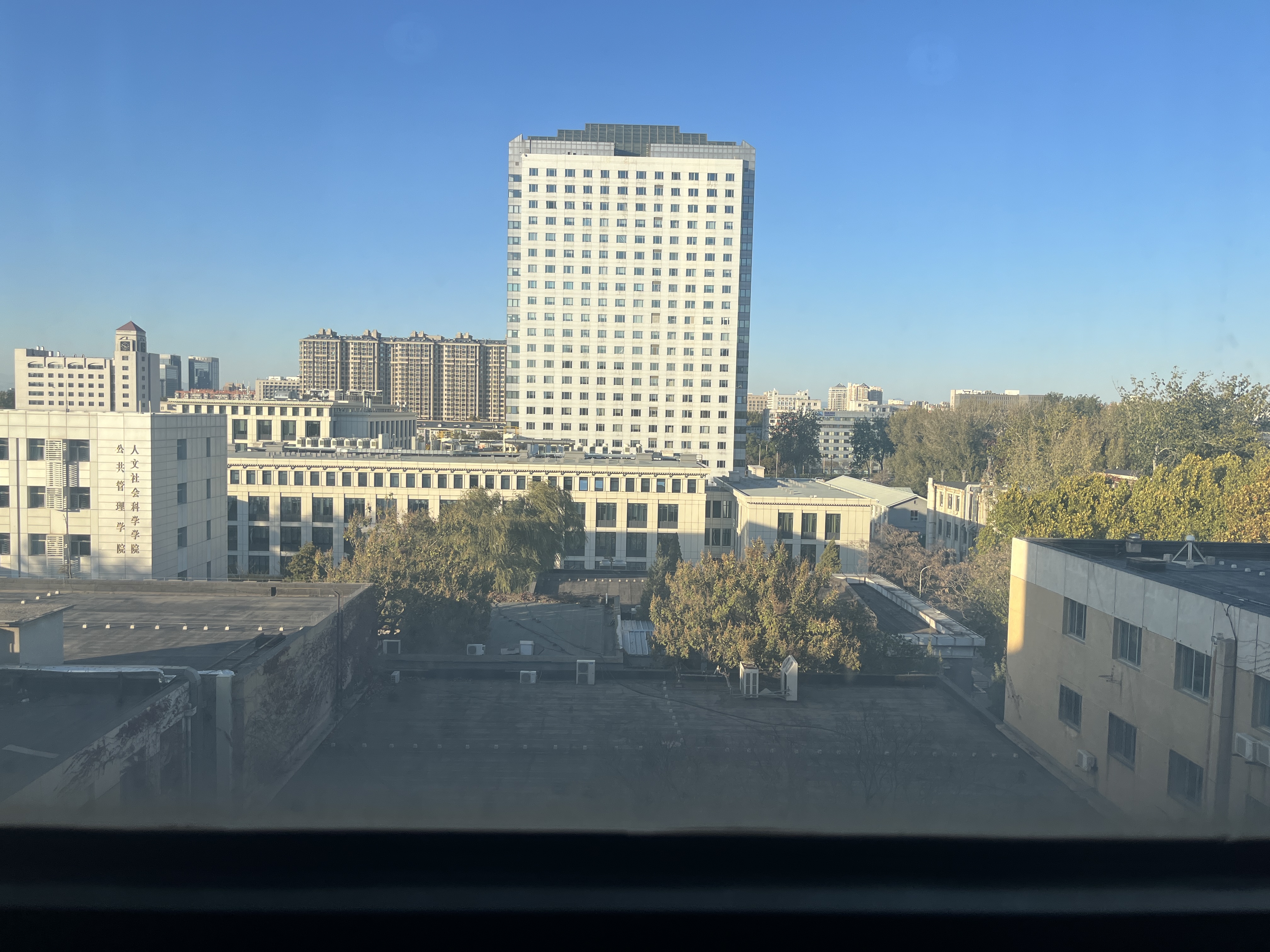 窗外风景。PS:在图书馆六楼东中文阅览室，窗边有一排小圆桌。倘若天气晴朗，坐在桌边，只一转头、轻松便能望到很远很远的地方。冬日的阳关柔和，即便没有百叶窗的遮拦，也不会感到刺眼。这大概是能让我在慵懒的周末从床上爬起来的最大动力了吧:) 